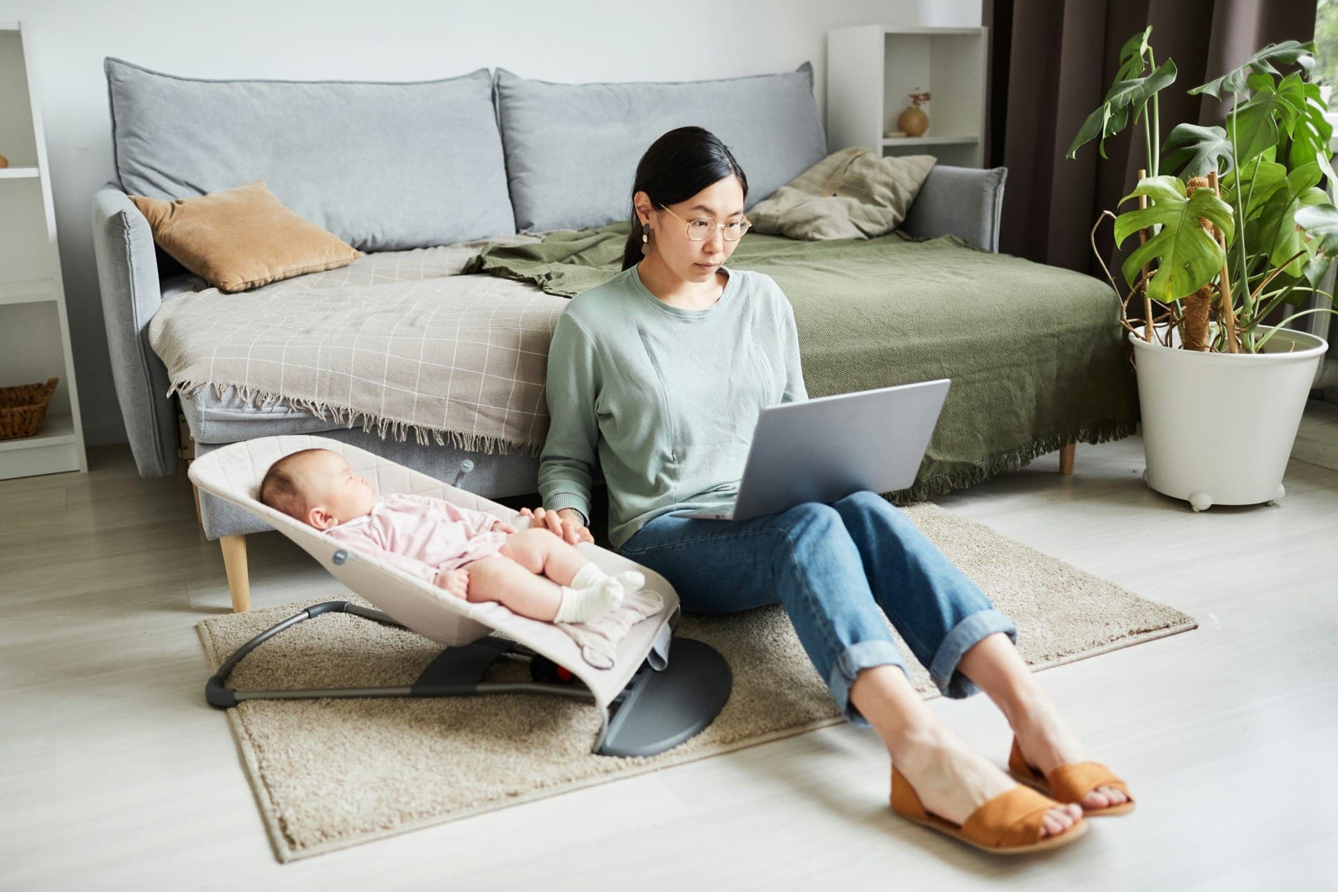 Woman with baby using laptop at home